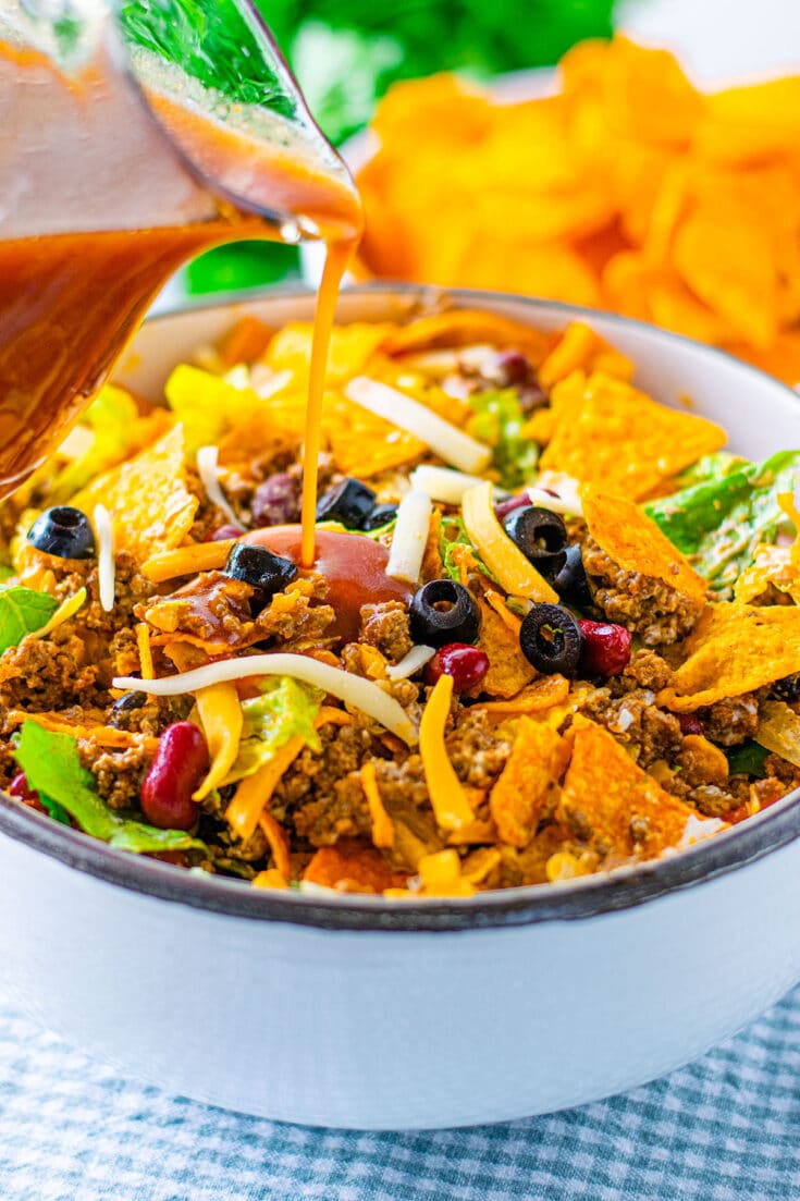 Dorito taco salad with catalina dressing being poured to toss and serve