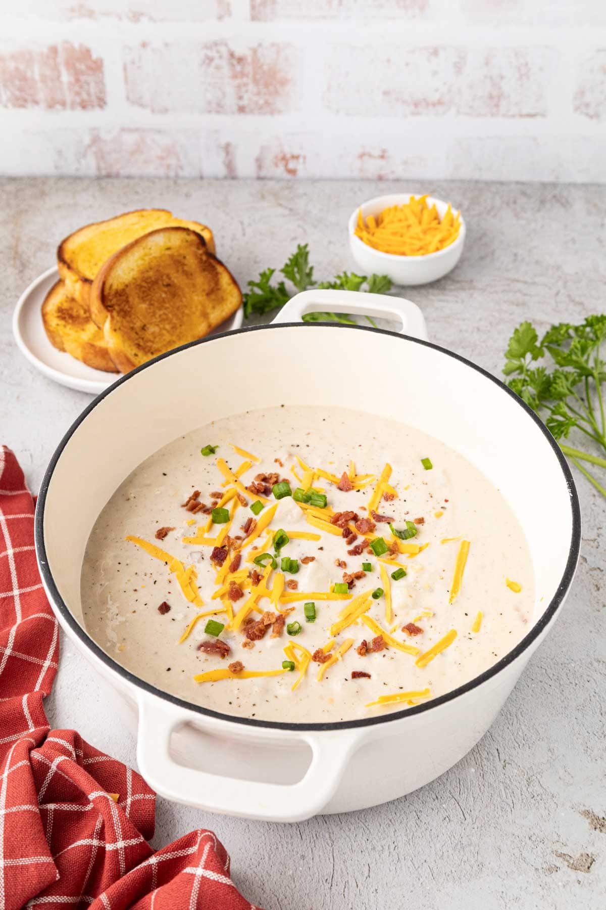 Loaded potato soup and a white enamel Dutch oven with a black rim.