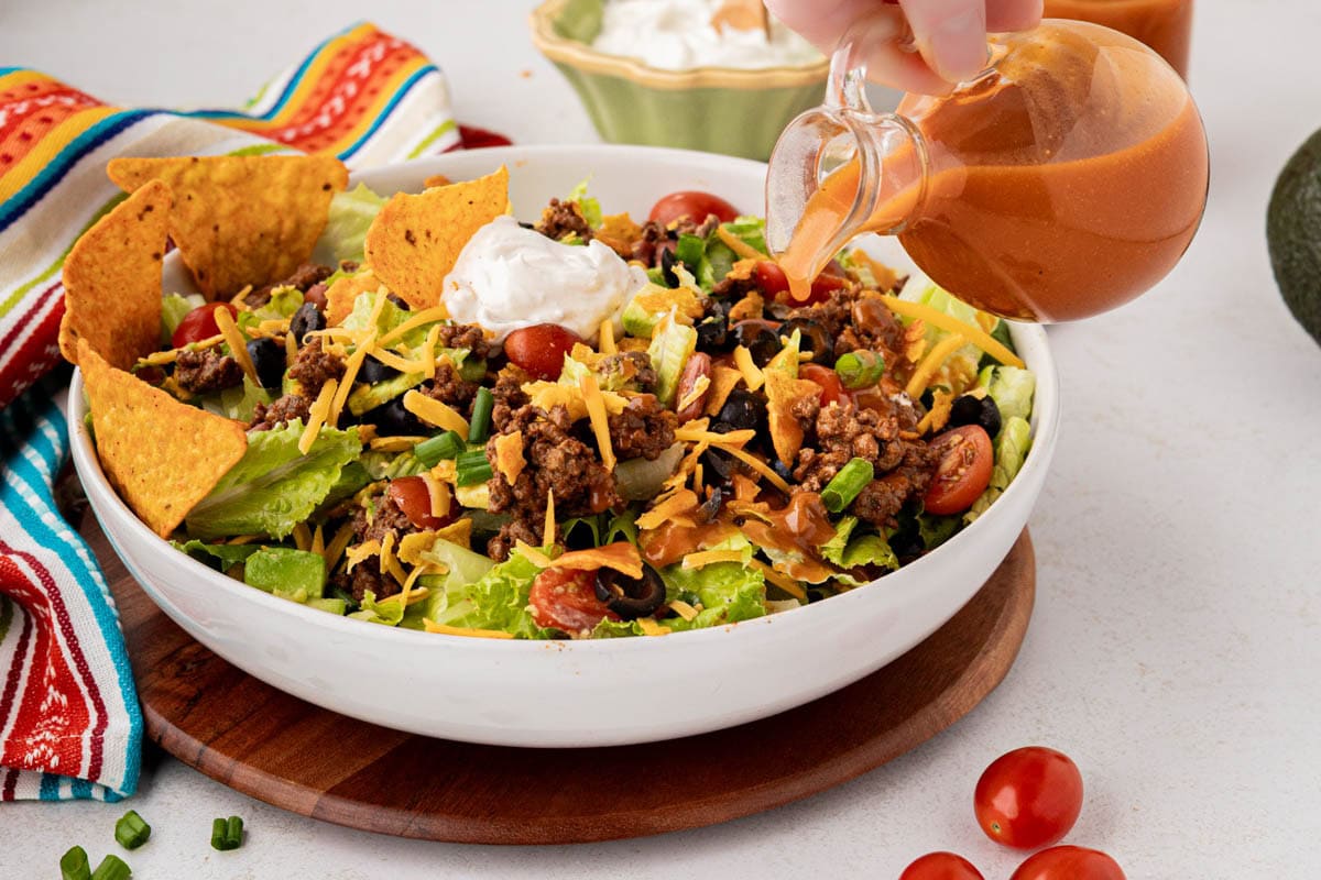 Pouring Catalina dressing over top of the taco salad.