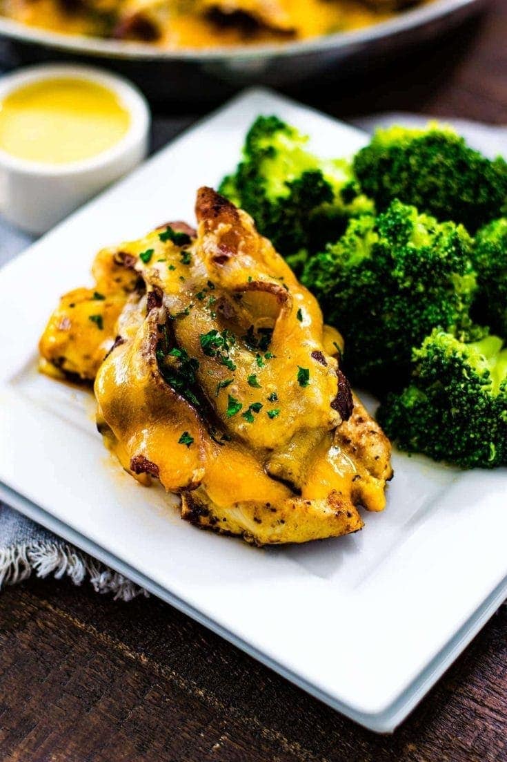 Alice Springs Chicken - a flavorful chicken breast topped with a honey mustard sauce, mushroom, cheese, and bacon is set on a plate with steamed brocoli. 