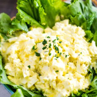 this classic egg salad served on top of fresh lettuce leaves in a large blue serving bowl