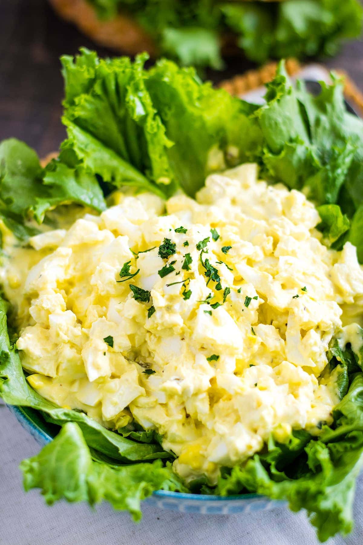 this classic egg salad served on top of fresh lettuce leaves in a large blue serving bowl