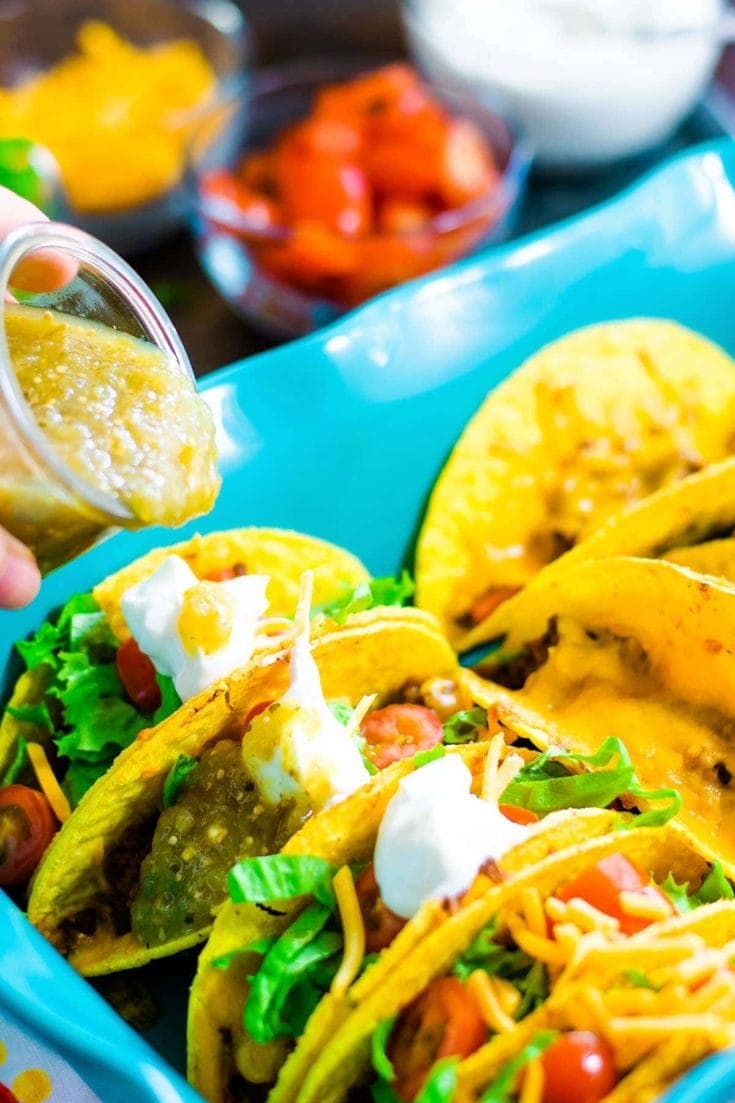 Pouring salsa verde on oven baked tacos