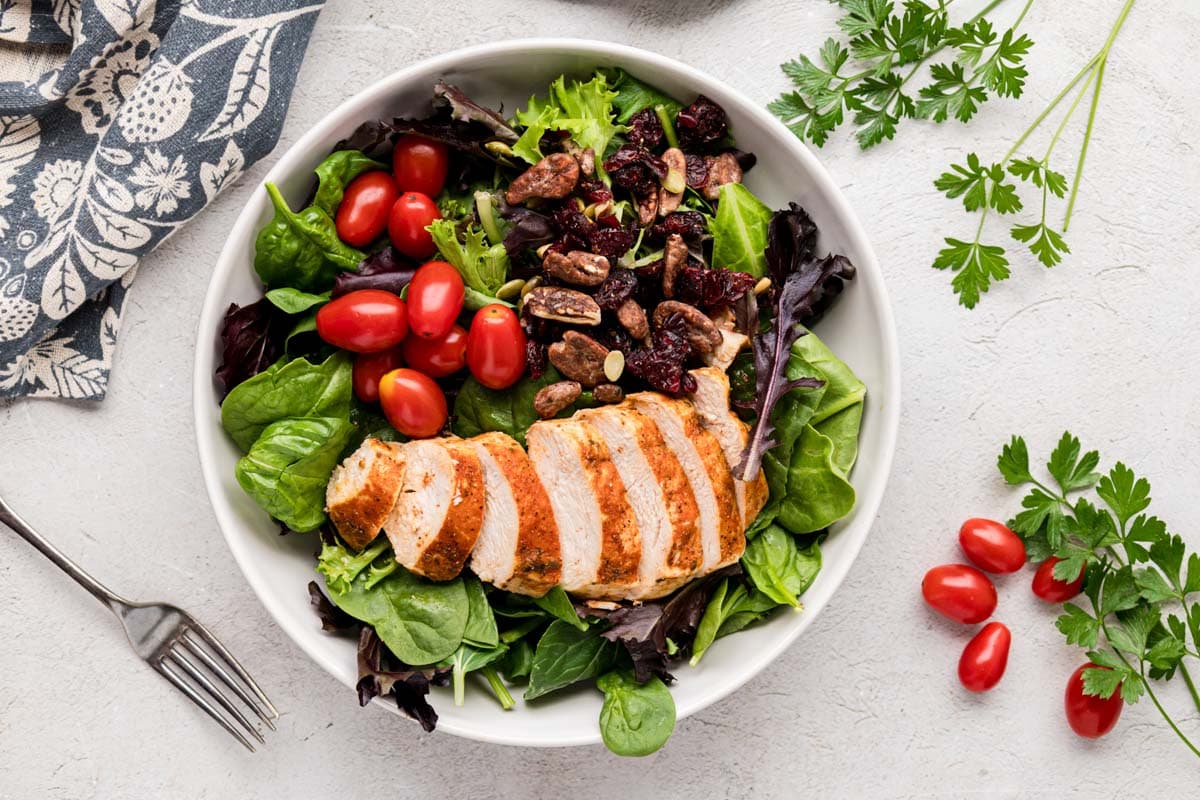 Instant Pot chicken breasted sliced and serve on a salad in a white salad bowl.