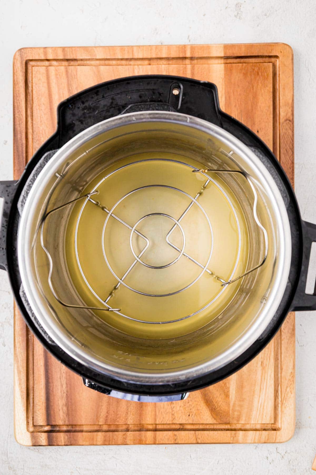 Broth in the bottom of the instant pot with a trivet on top.