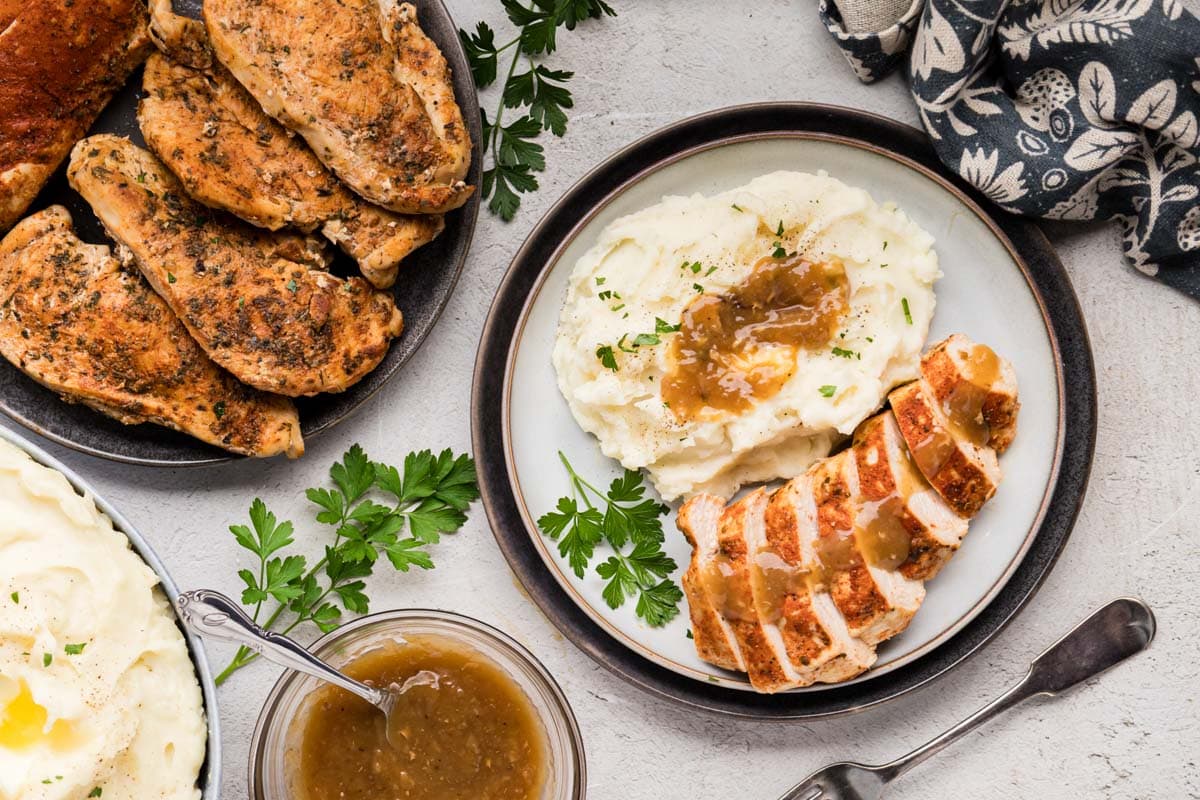 A plate with sliced instant pot chicken breast served with mashed potatoes and instant pot chicken gravy.