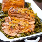 A plate of pulled pork on top of collard greens.