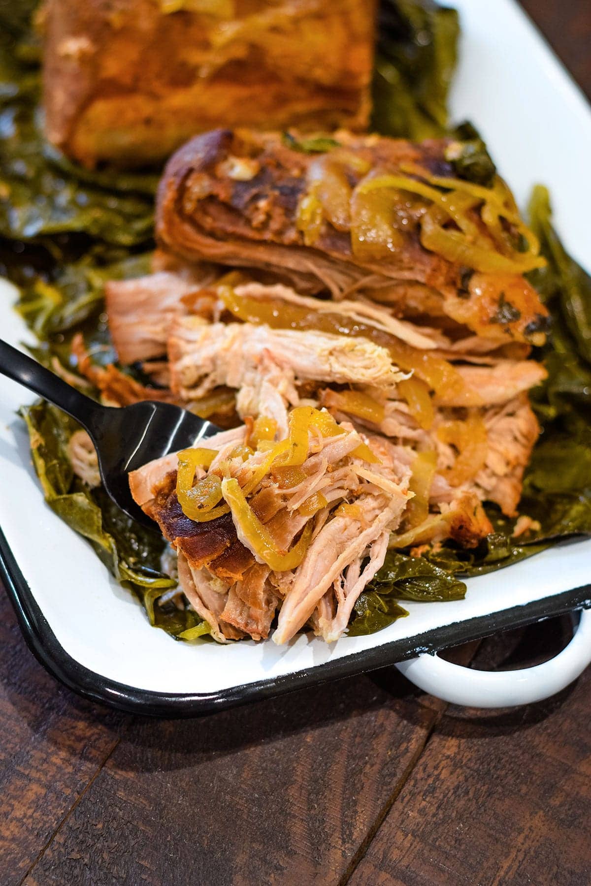 Collard Green Wrapped Pork Roast on white serving tray