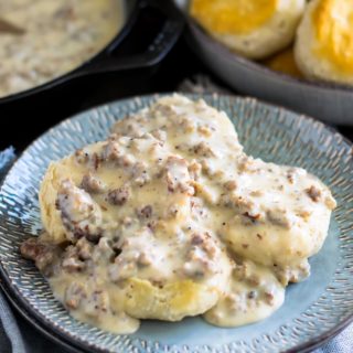 A bowl of sausage gravy on top of biscuits.