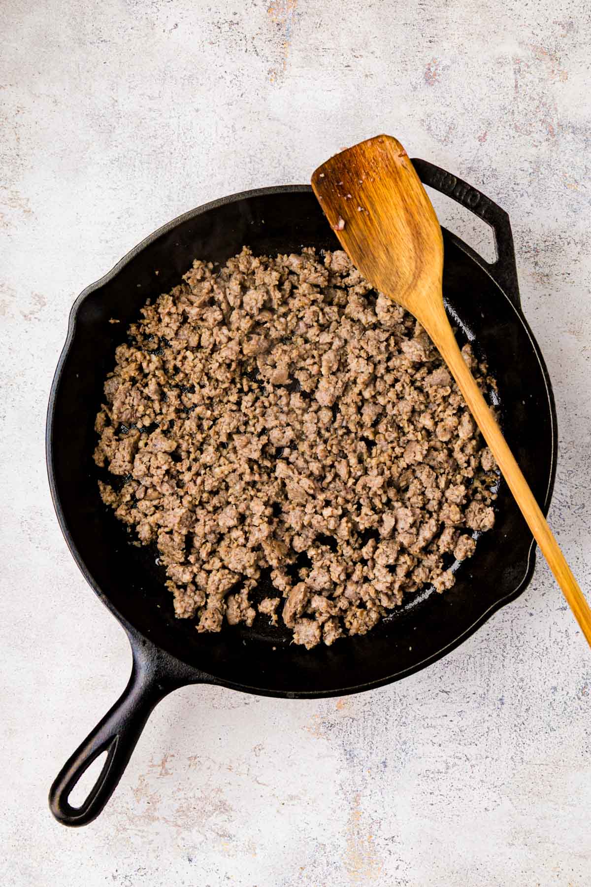 Cooked breakfast sausage crumbled in a cast iron skillet.