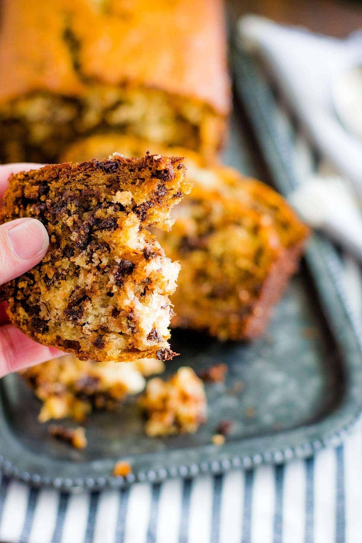 Hand holding banana bread with bite taken out of it.