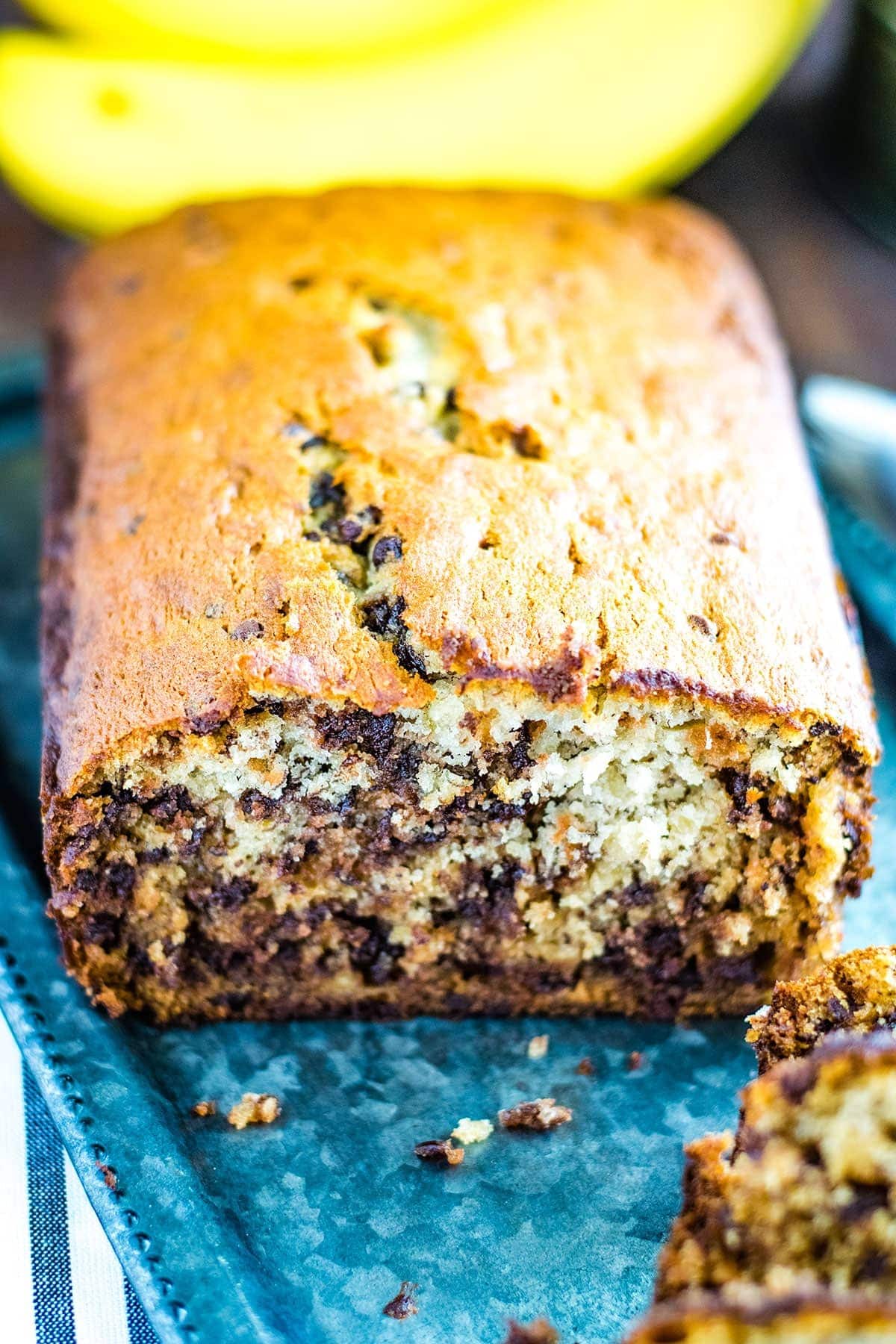 A cut loaf of banana bread with chocolate chips on a silver platter.