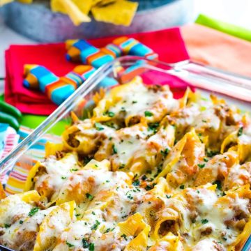 A clear baking dish filled with Mexican stuffed shells.