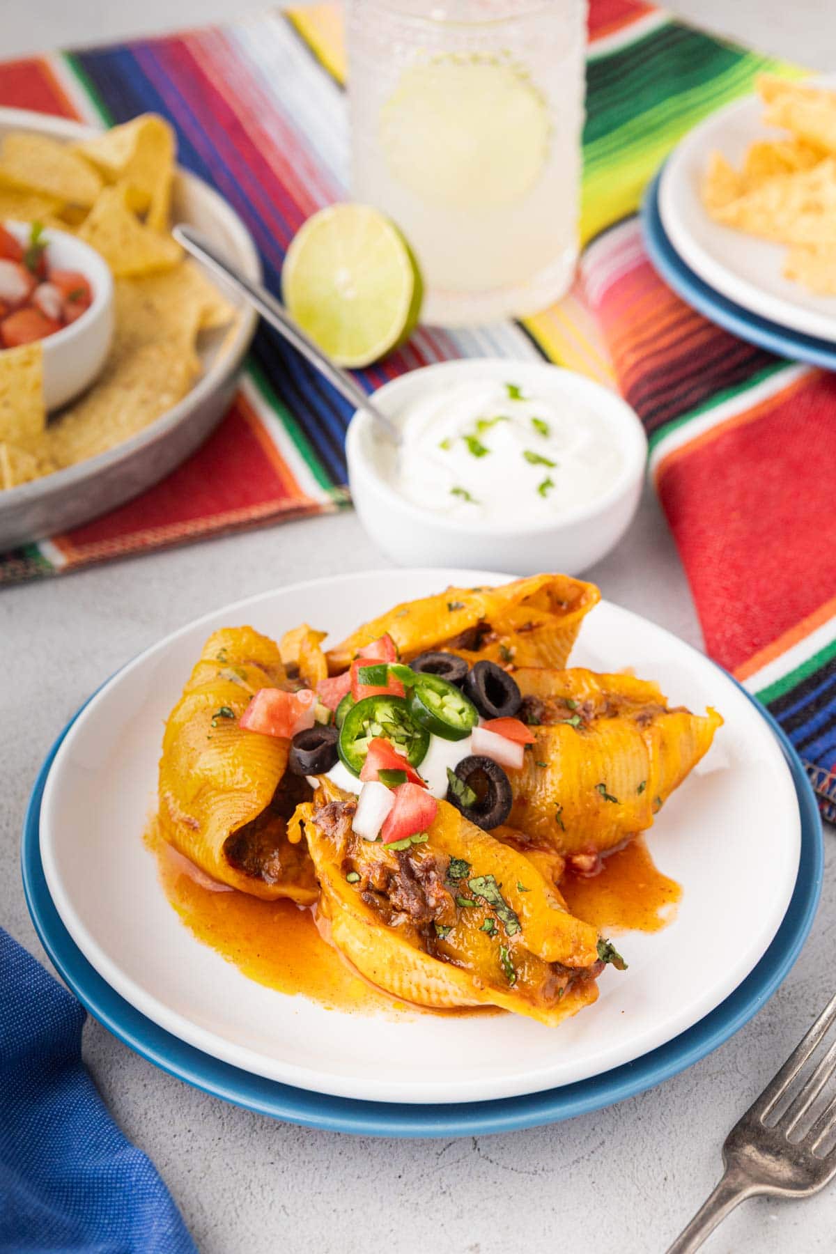 A plate of Taco Stuffed Shells with sour cream, pico, and jalapeno slices.
