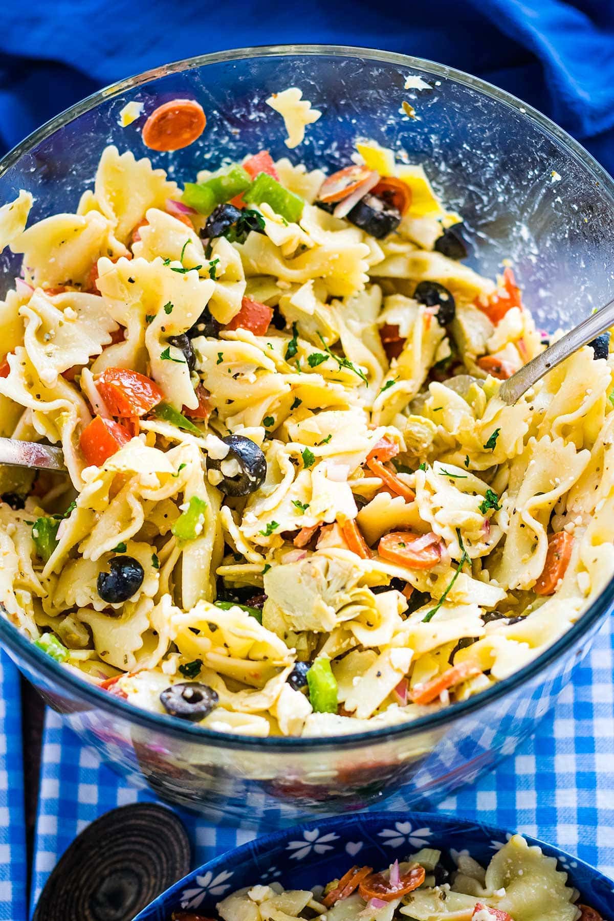 Artichoke and feta tossed pasta salad in a clear glass servign bowl