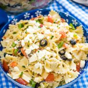 A blue bowl with Pasta salad in it on a blue checkered table setting.