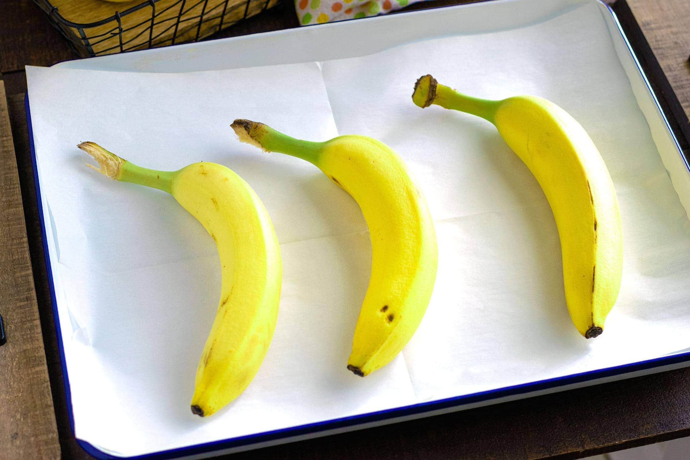 Three yellow bananas on a baking sheet