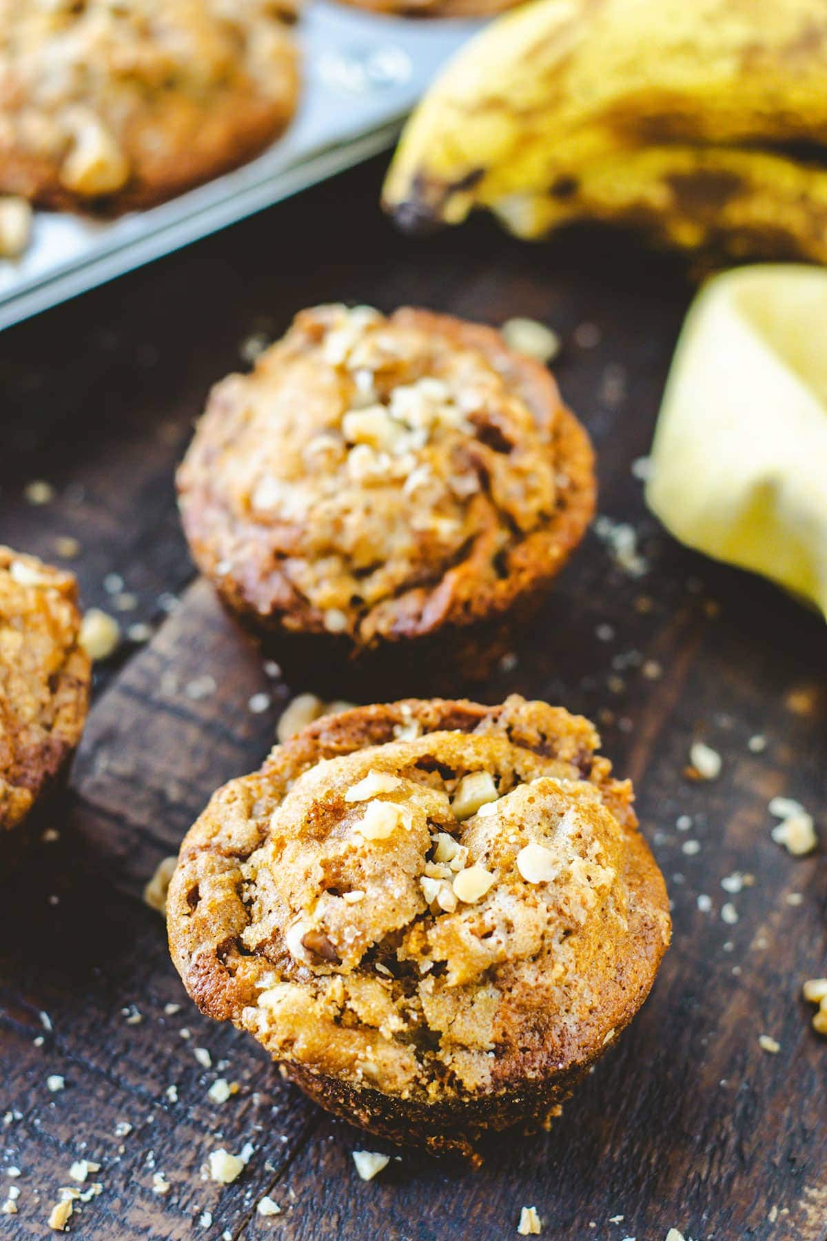 Banana Muffins topped with walnuts on a rustic tray.