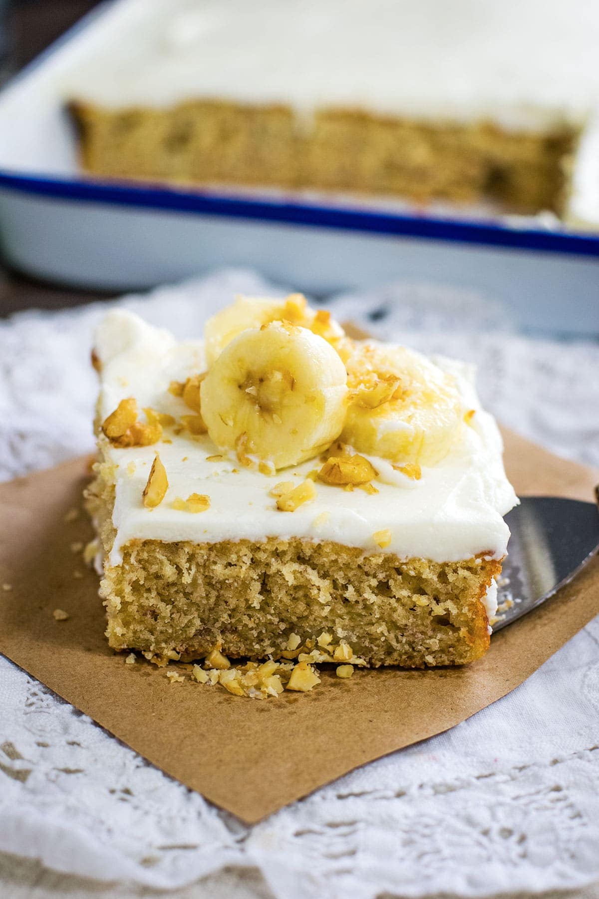 Slice of banana cake topped with bananas and walnuts