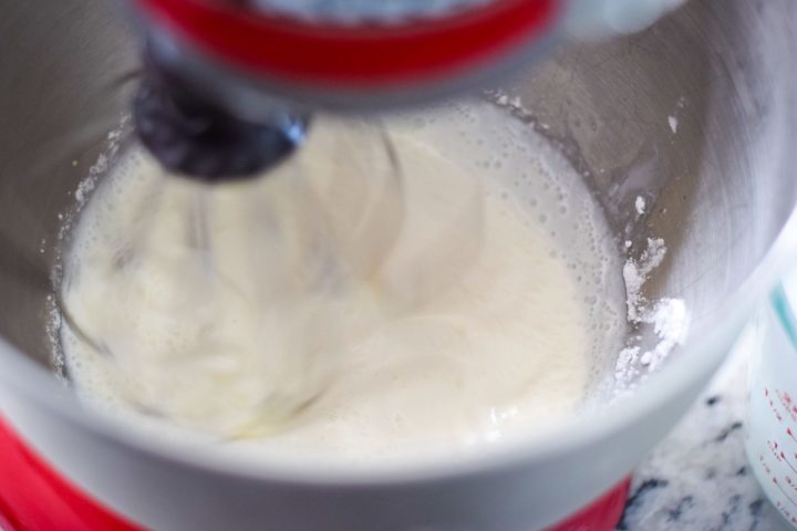 Whipping cream beginning to be whipped in a stand mixer.