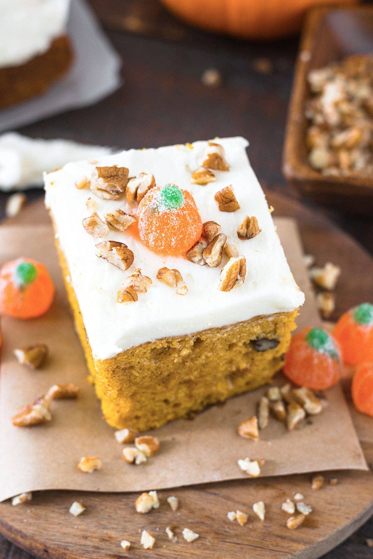 Slice of pumpkin cake topped with whimsical candy pumpkins and and pecan pieces. 