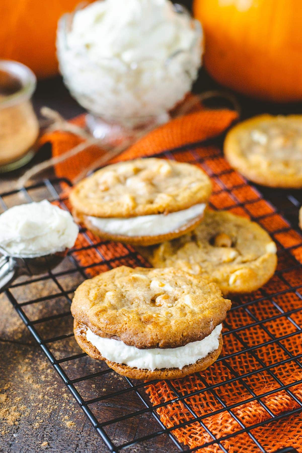 Two pumpkin spice whoopie cookies on a tray with orange burlap ribbon underneath.