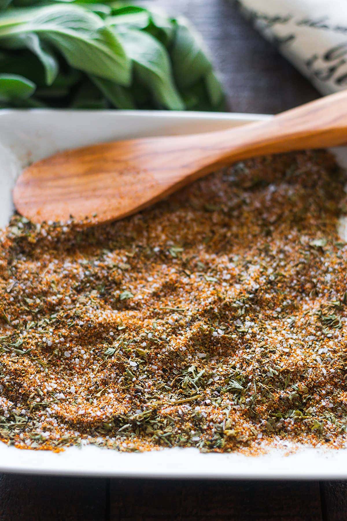 Turkey rub spices blended on a white plate with a wooden spoon in the background.