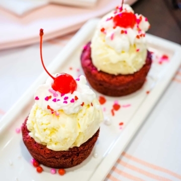 A close-up of red velvet brownie cups topped with ice cream on a plate.