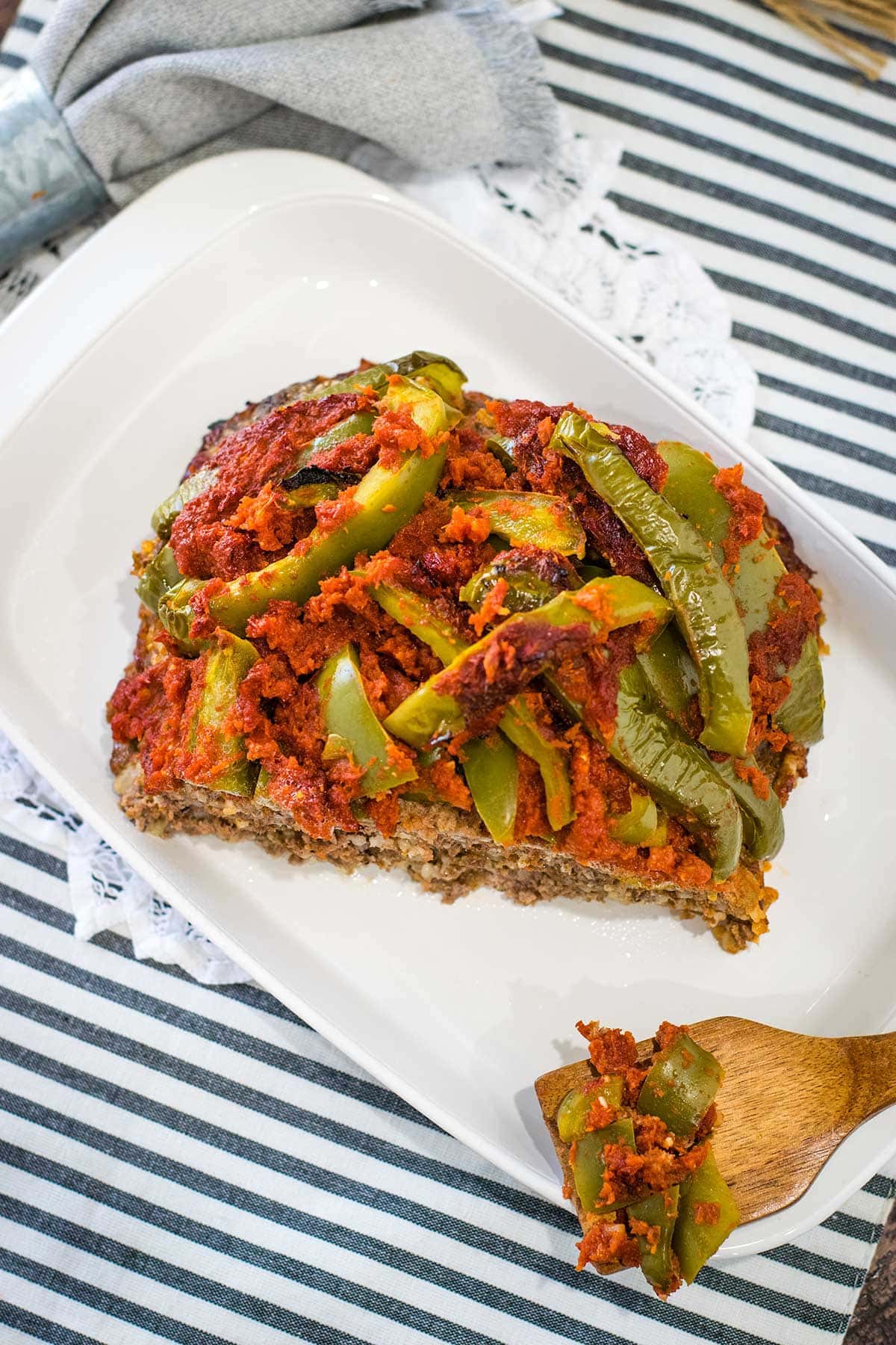 Stuffed peppers meatloaf situation on a plate at a table setting. 