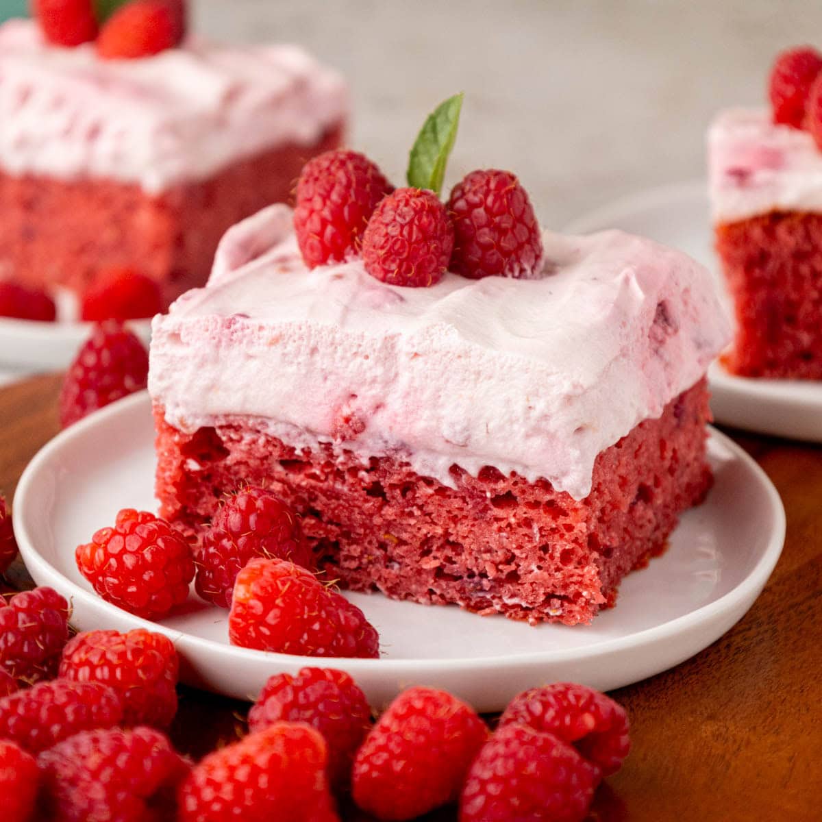 Slice of raspberry fluff cake with raspberries on a white plate.