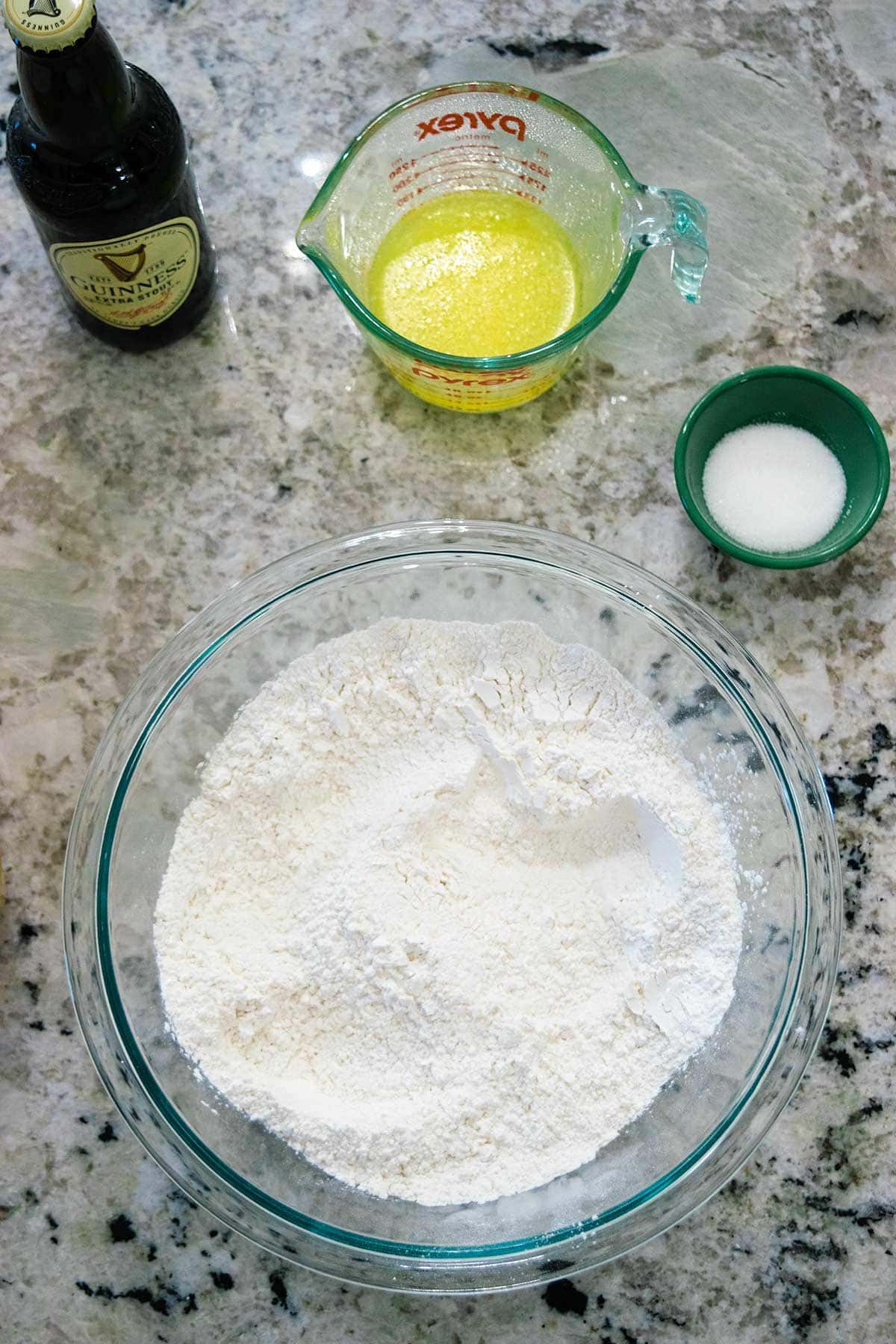 Picture of ingredients to make beer bread. Bottle of beer, melted butter, sugar and self rising flour.