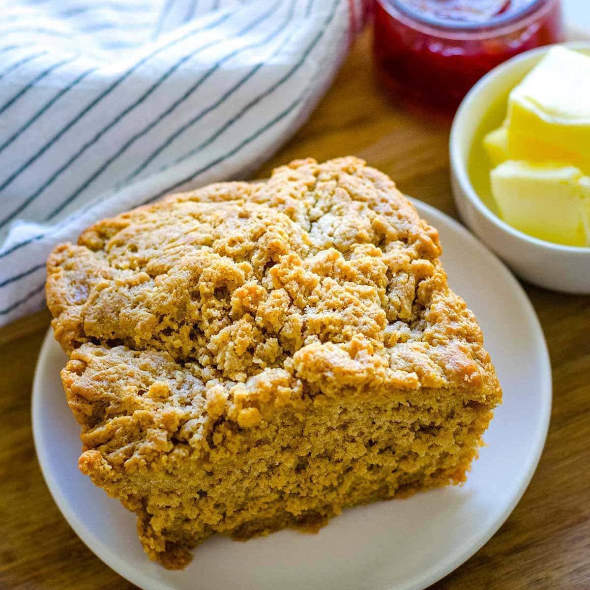A plate of beer bread on a table, with jam and butter.