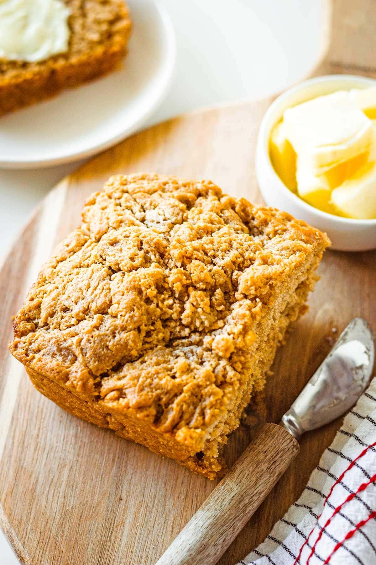 Half a loaf of beer bread on a cutting board with a butter and a serving knife. 