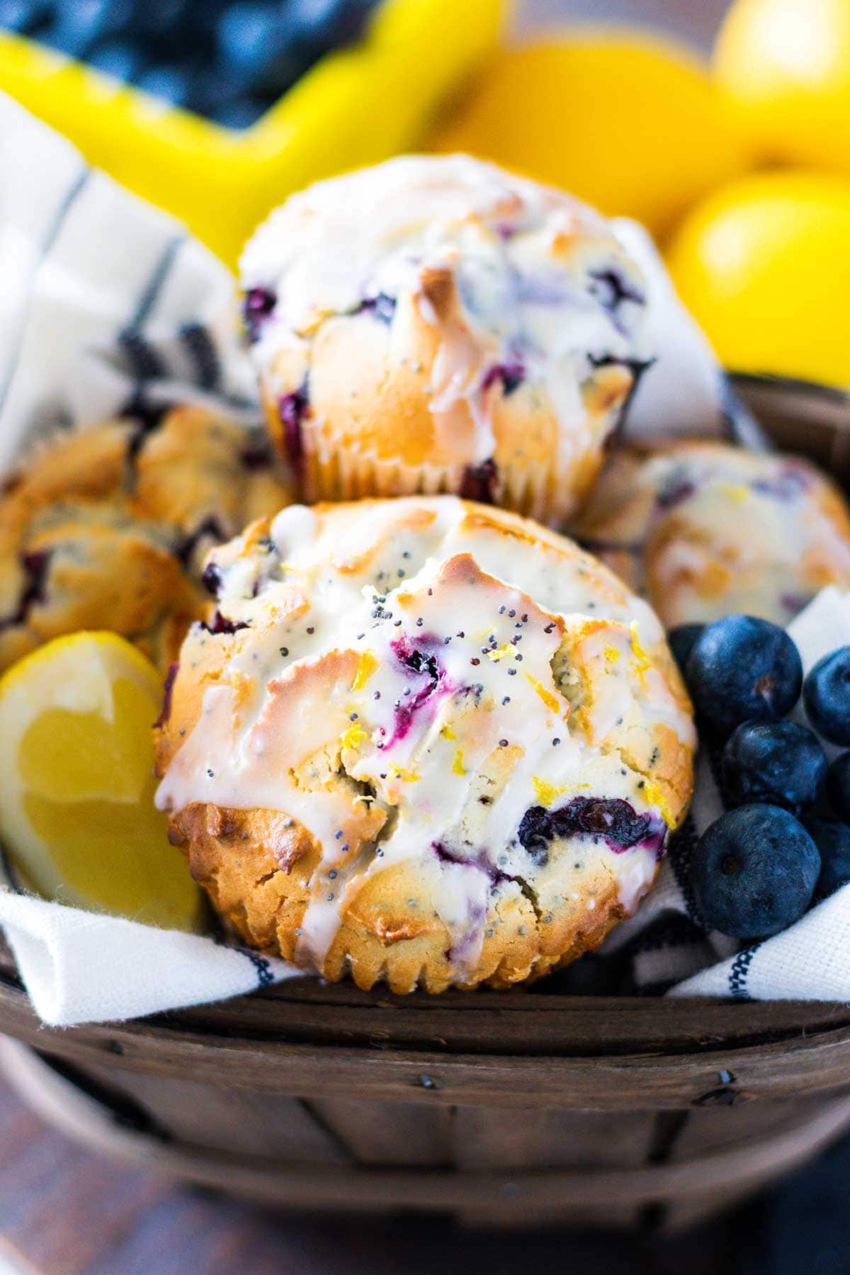 A basket filled with blueberry lemon poppy seed muffins and garnished with a lemon slice and blueberries.