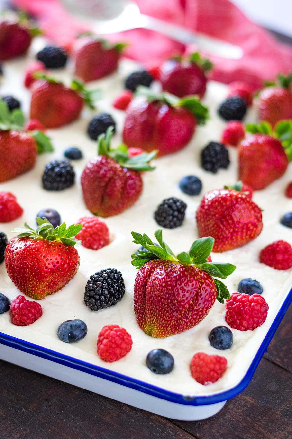 Up close image of chantilly sheet cake topped with fresh strawberries, raspberries, blueberries and blackberries.