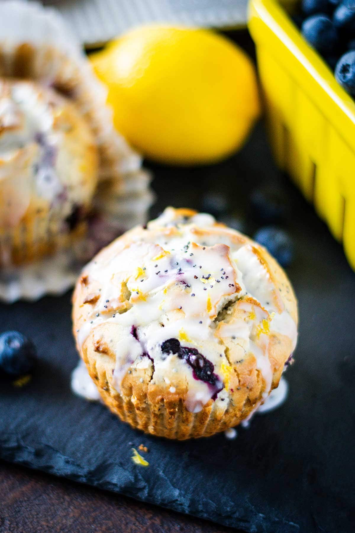 Blueberry lemon poppy seed muffin on a black tray with blueberries in the background.