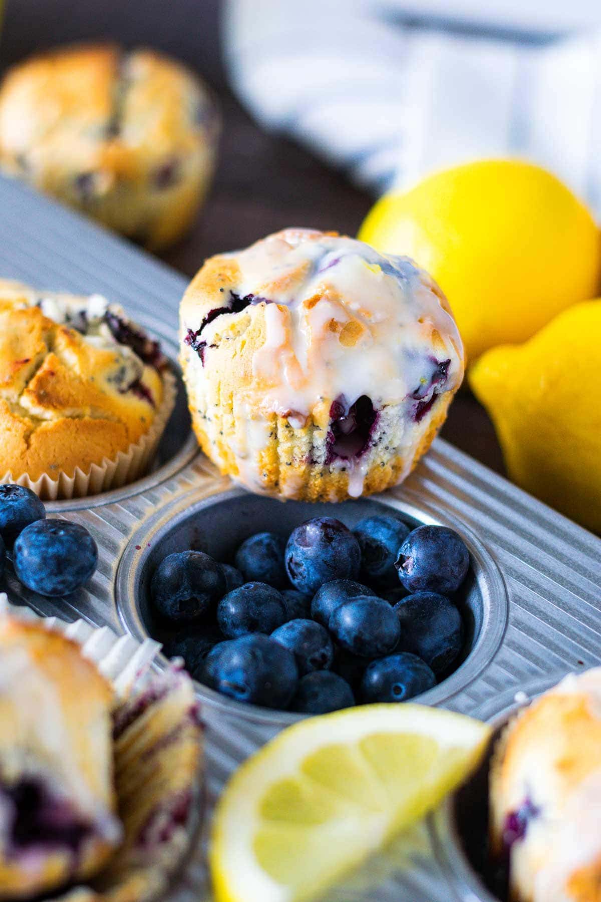 Blueberry Lemon Muffin on a table, with lemon in the background and blueberries scattered