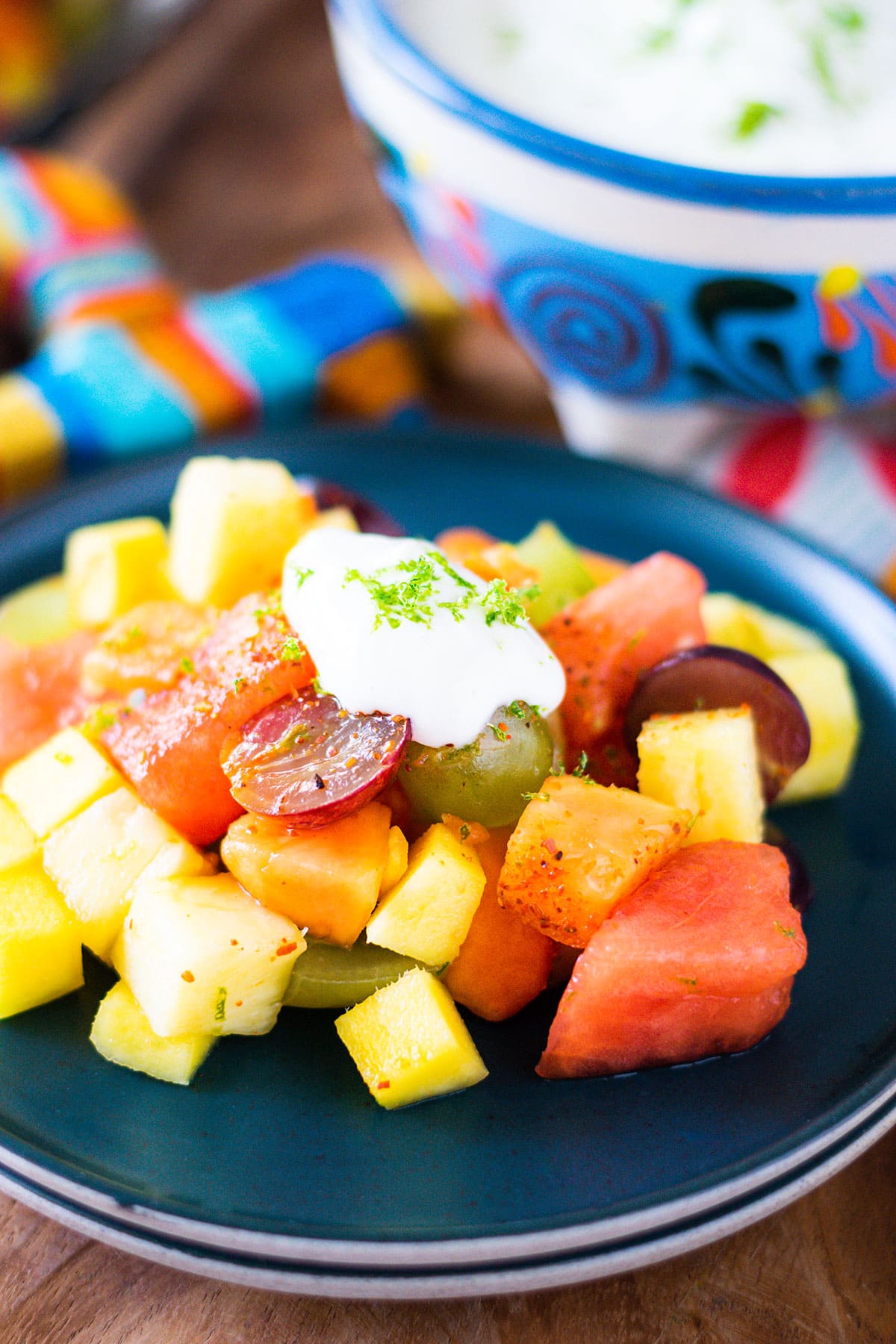 Plated Mexican fruit salad with lime yogurt dolloped on top.