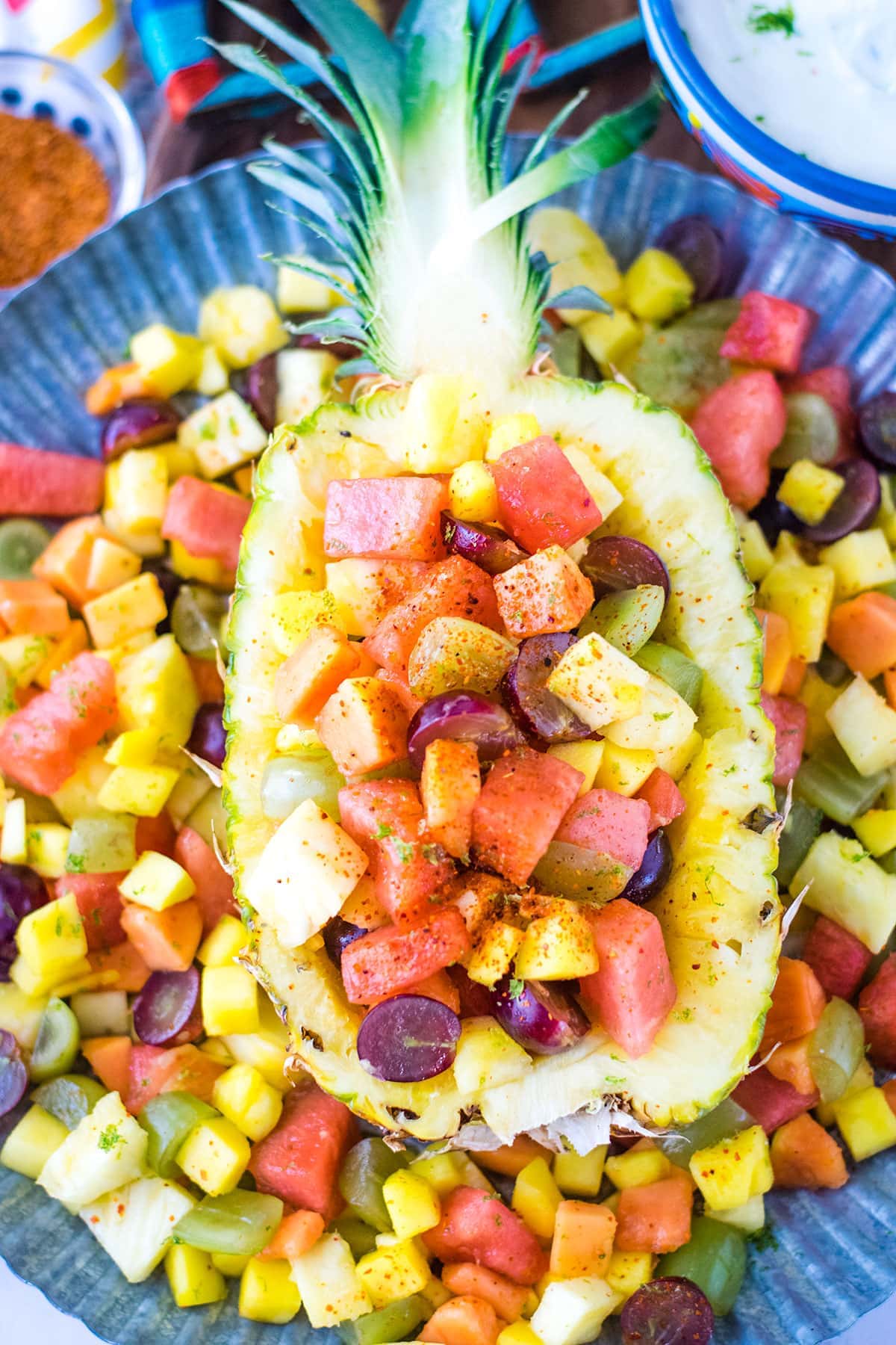 Half pineapple with Mexican fruit salad sprinkled with chili lime seasoning on top.