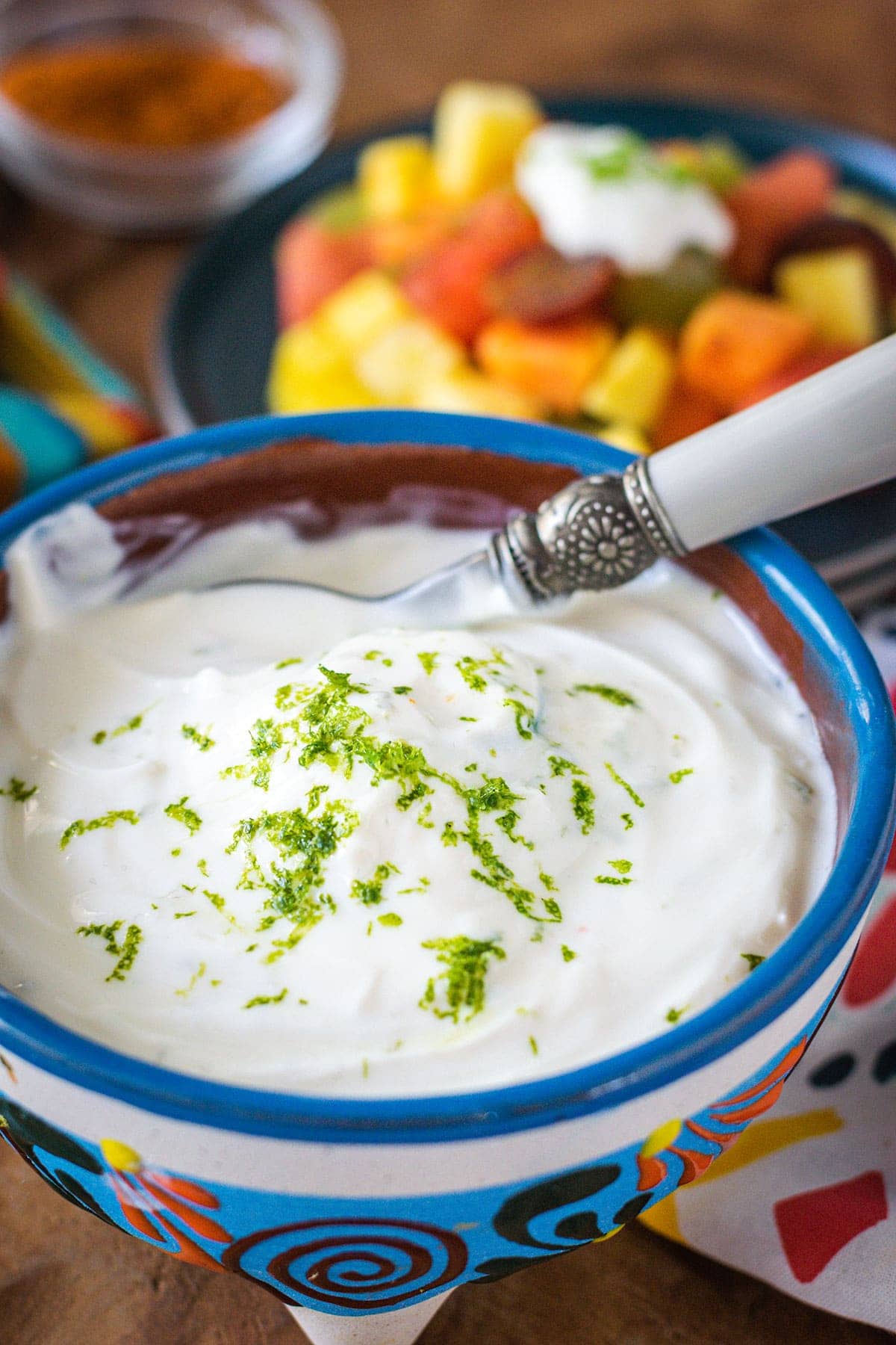 Upclose image of lime yogurt dip with a serving spoon and fruit in the background.