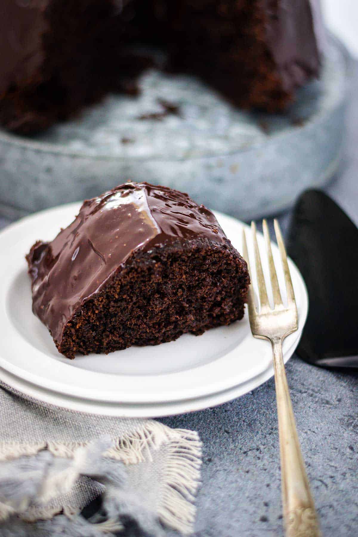 Chocolate brownie cake with a fork to the side. Place on a gray tablescape with a black cake server..