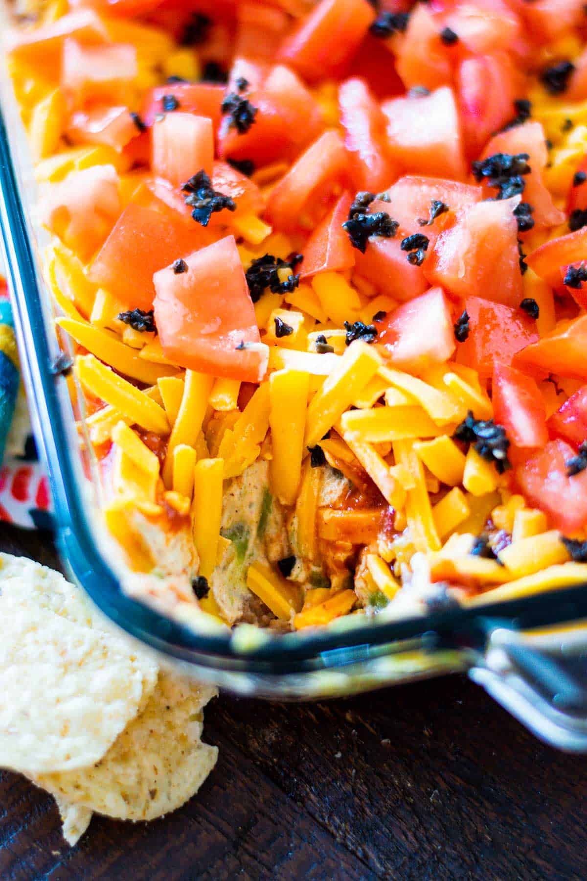 Mexican layer dip in a glass bowl with some of the dip removed.