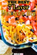 Pinterest image of a dish of Mexican Seven Layer Dip on a wooden table.