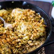 Cast-iron skillet with creamy swiss casserole being served with a serving spoon.