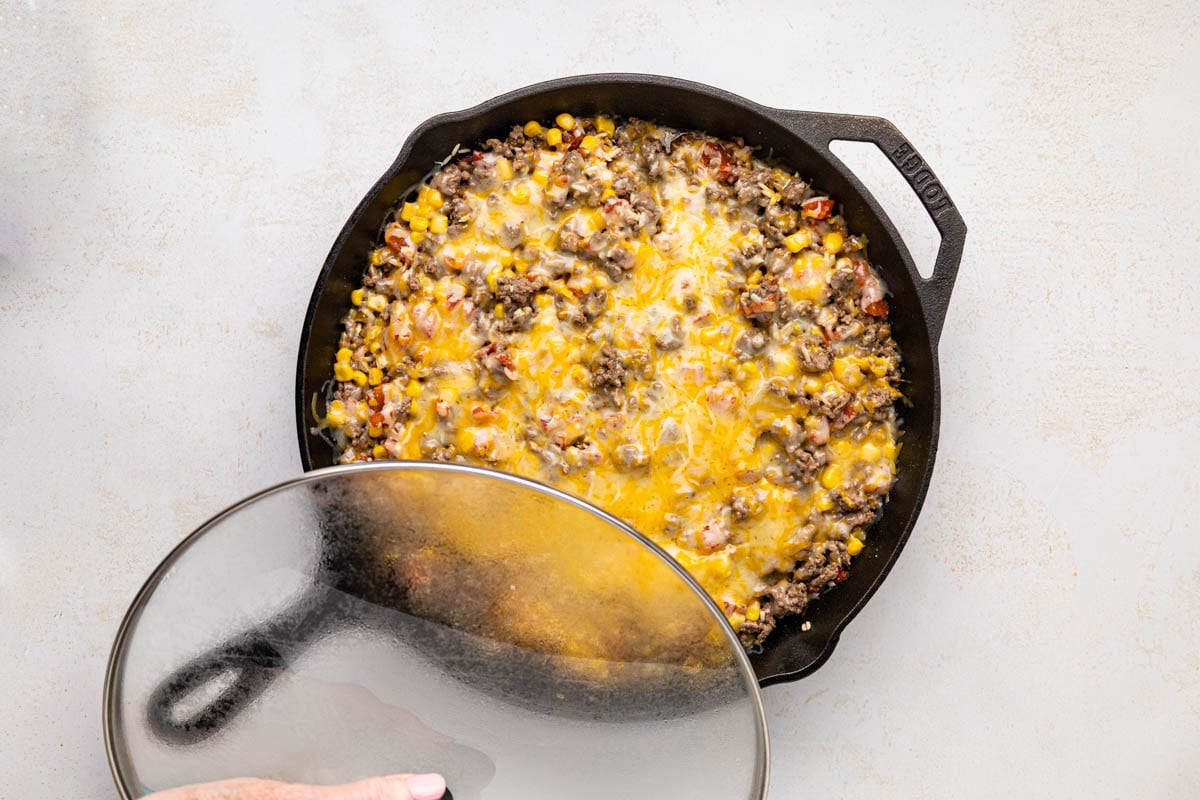 A lid being removed after the cheese has melted.