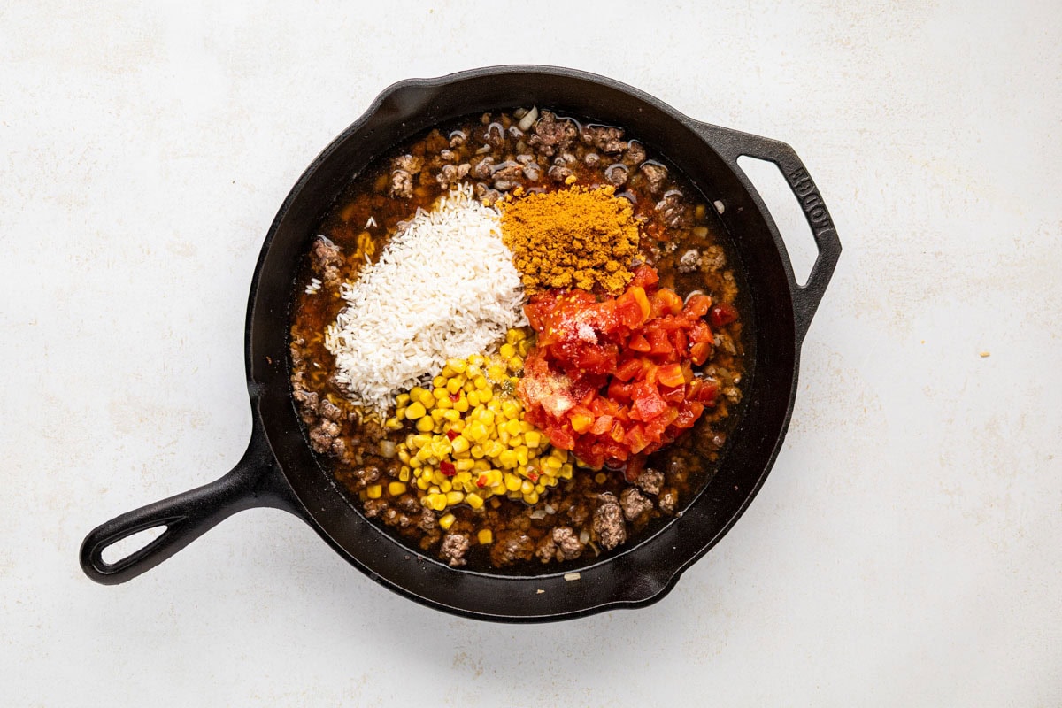 Taco seasoning, garlic powder, salt, rinsed rice, drained corn, Rotel (undrained), and beef broth add to the skillet.
