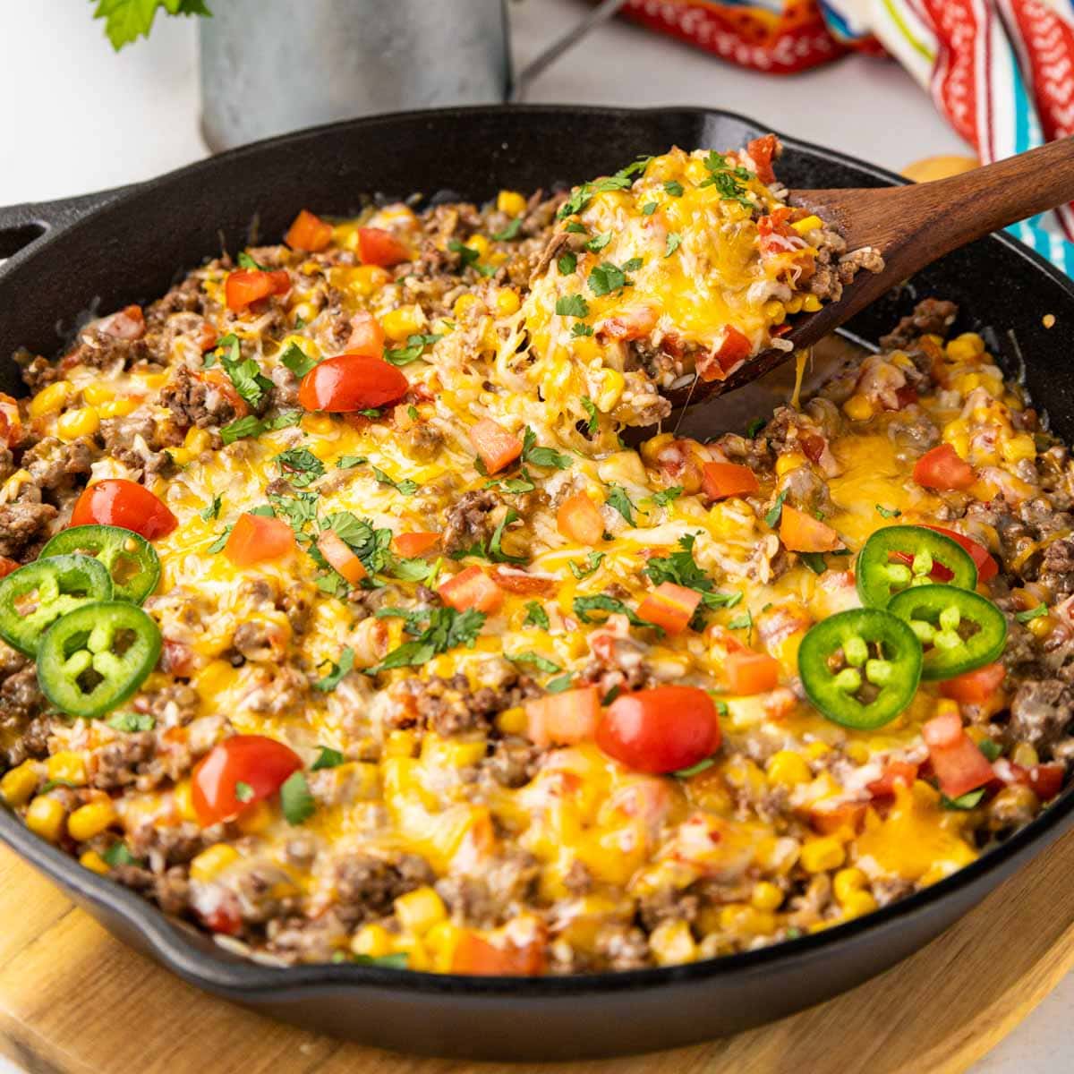 A spoon taking a serving of Mexican Beef and rice in a cast iron skillet.