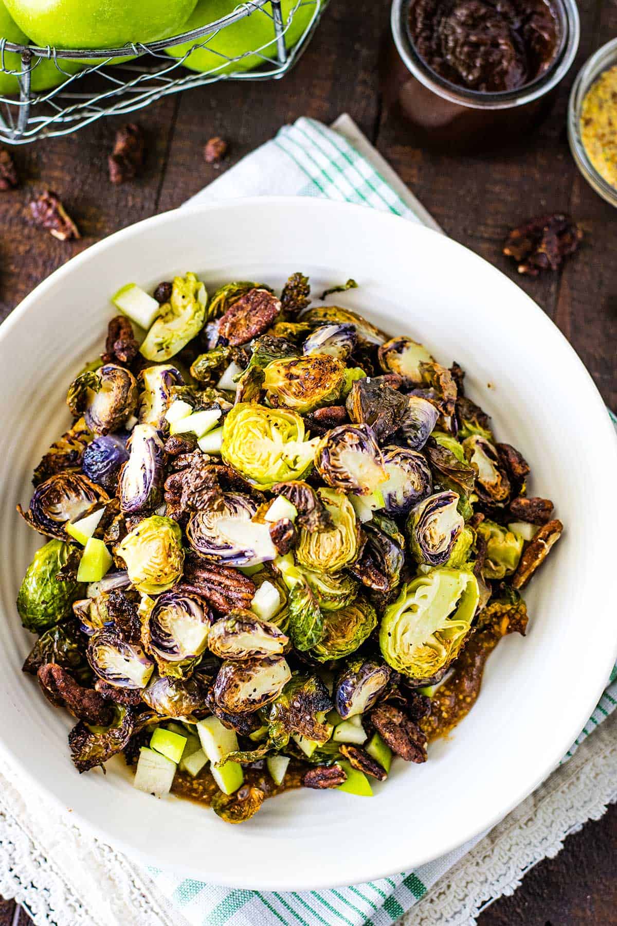 Overhead image of roasted brussels sprouts in a white bowl on a wooden table.