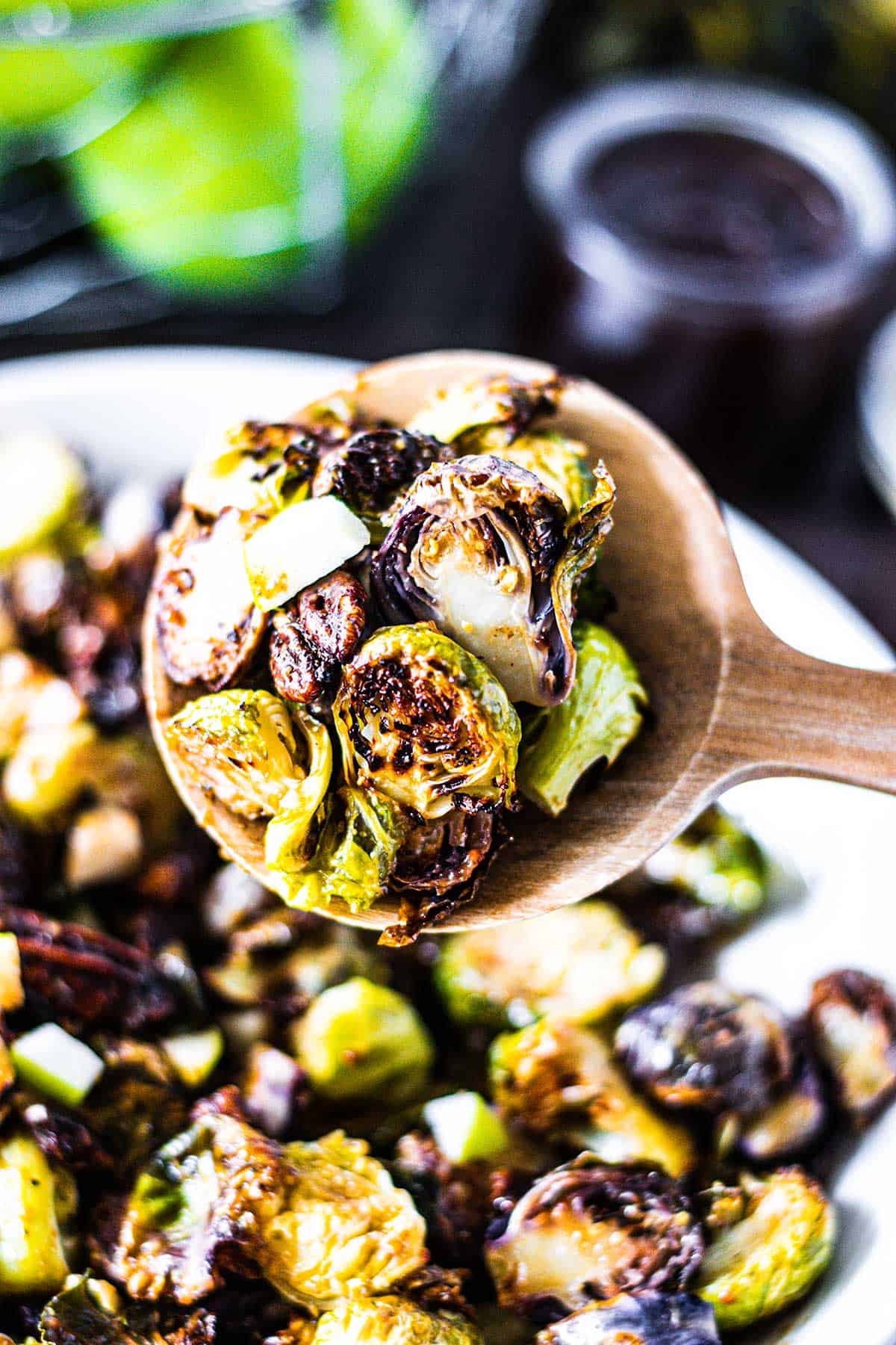 Upclose image of brussels sprouts being scooped on a wooden serving spoon.