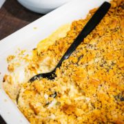 A white casserole dish with chicken poppy seed casserole scooped out of it.